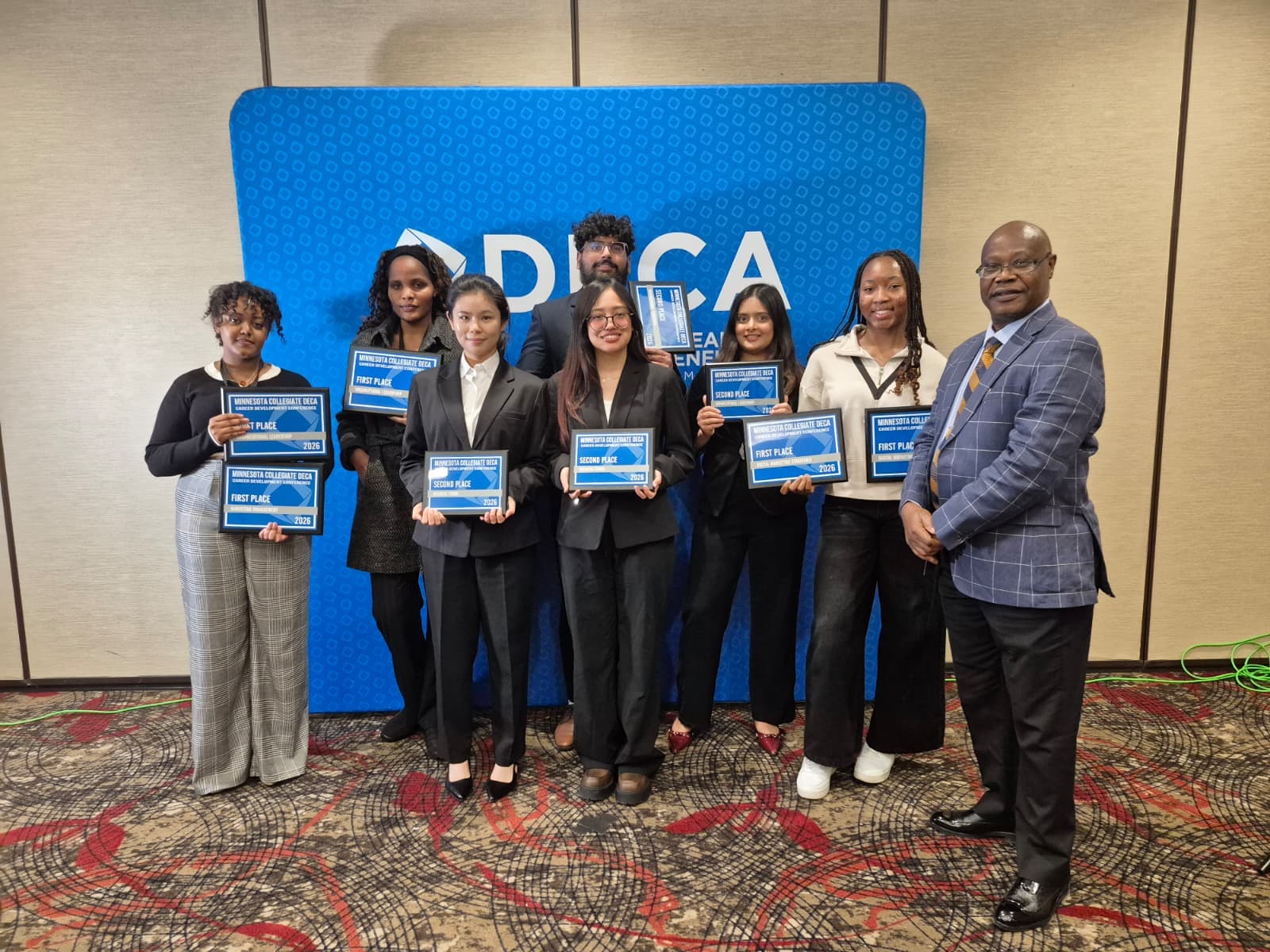 SMSU DECA competitors and Dr. Chukwuba holding 1st and 2nd place plaques at CDC 2026